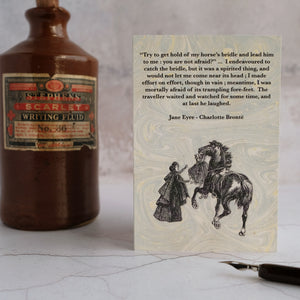 Jane Eyre quotation card beside stone ink bottle.